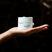Woman holding moisturizer in her hand with dark background